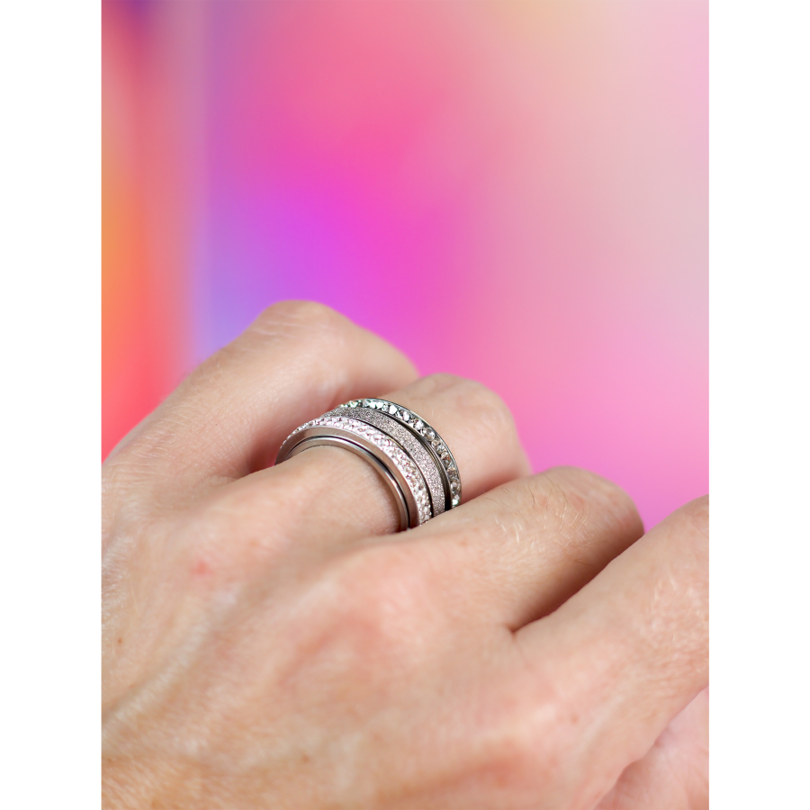 3 sølvfarvede Arlette anti-stress ringe fra LÉ MOSCH – med sten og drejefunktion, vist på hånd.