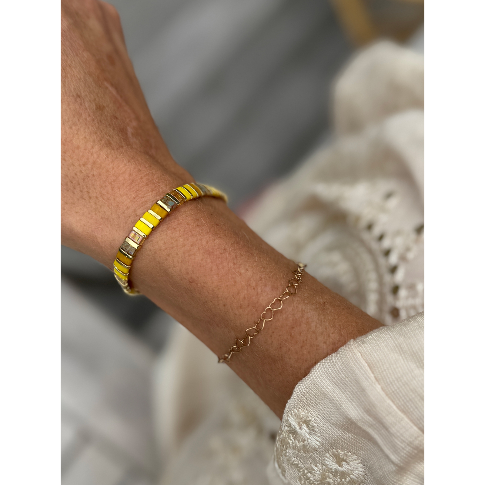 Gult og guld farvet Xia armbånd fra  LÉ MOSCH – med natursten, vist på hånd.
