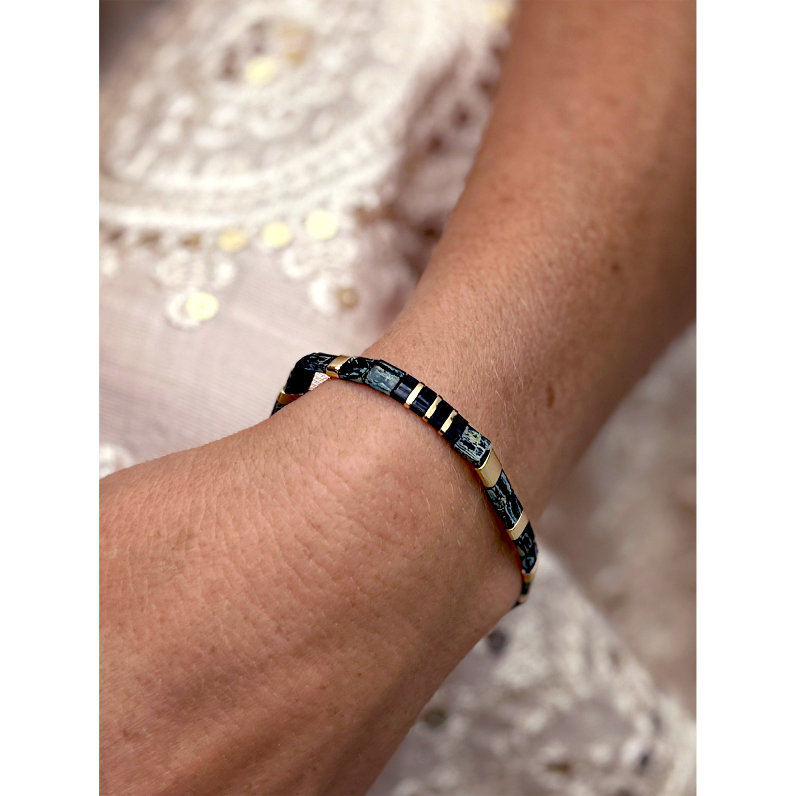 Sort og guld farvet Xia armbånd fra  LÉ MOSCH – med natursten, vist på hånd.