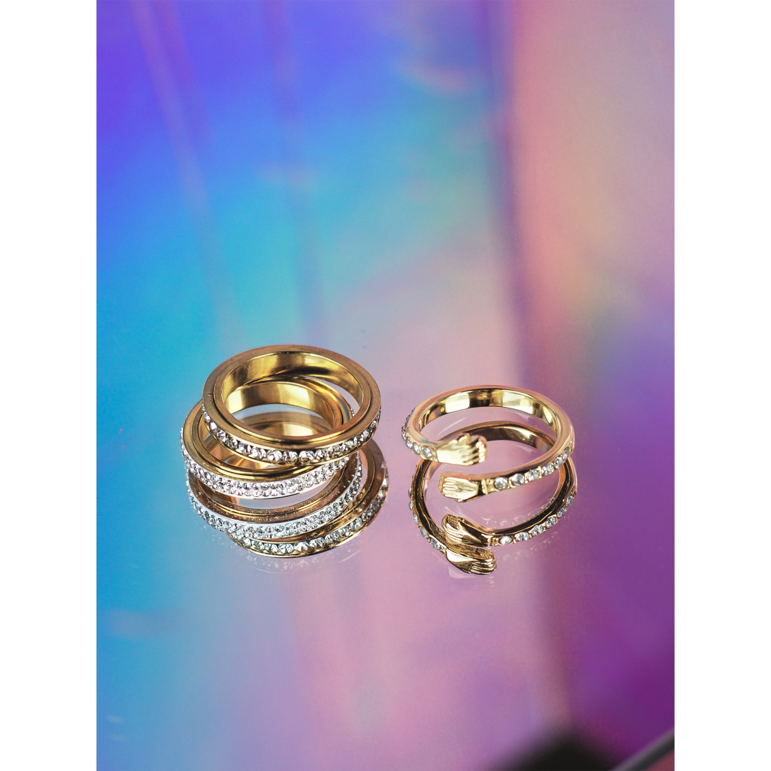 Forgyldte ringe med funklende zirkoner – elegant stacking-sæt fra LÉ MOSCH, fotograferet på farverig baggrund