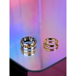 To elegante ringe fra LÉ MOSCH – én i sølv og én i guld med perledetaljer, placeret på spejl med lilla og pink baggrund